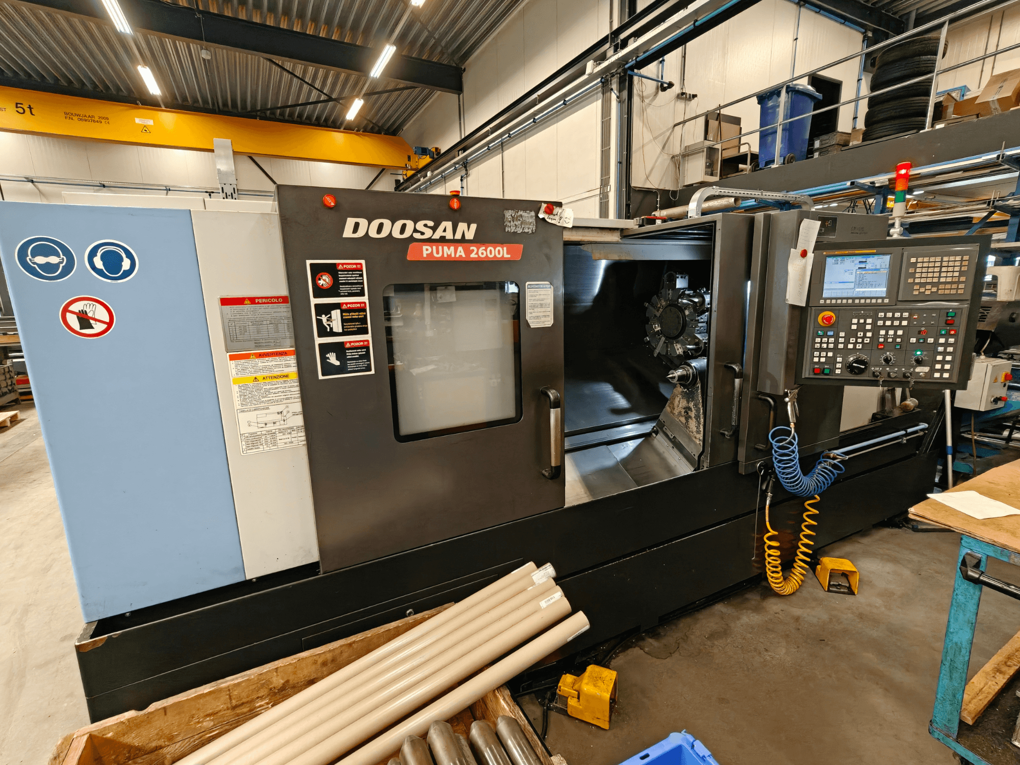 DOOSAN Puma 2600L vízszintes esztergagép egy műhelyben, oldalnézetben a vezérlőpanel és az orsó területe.