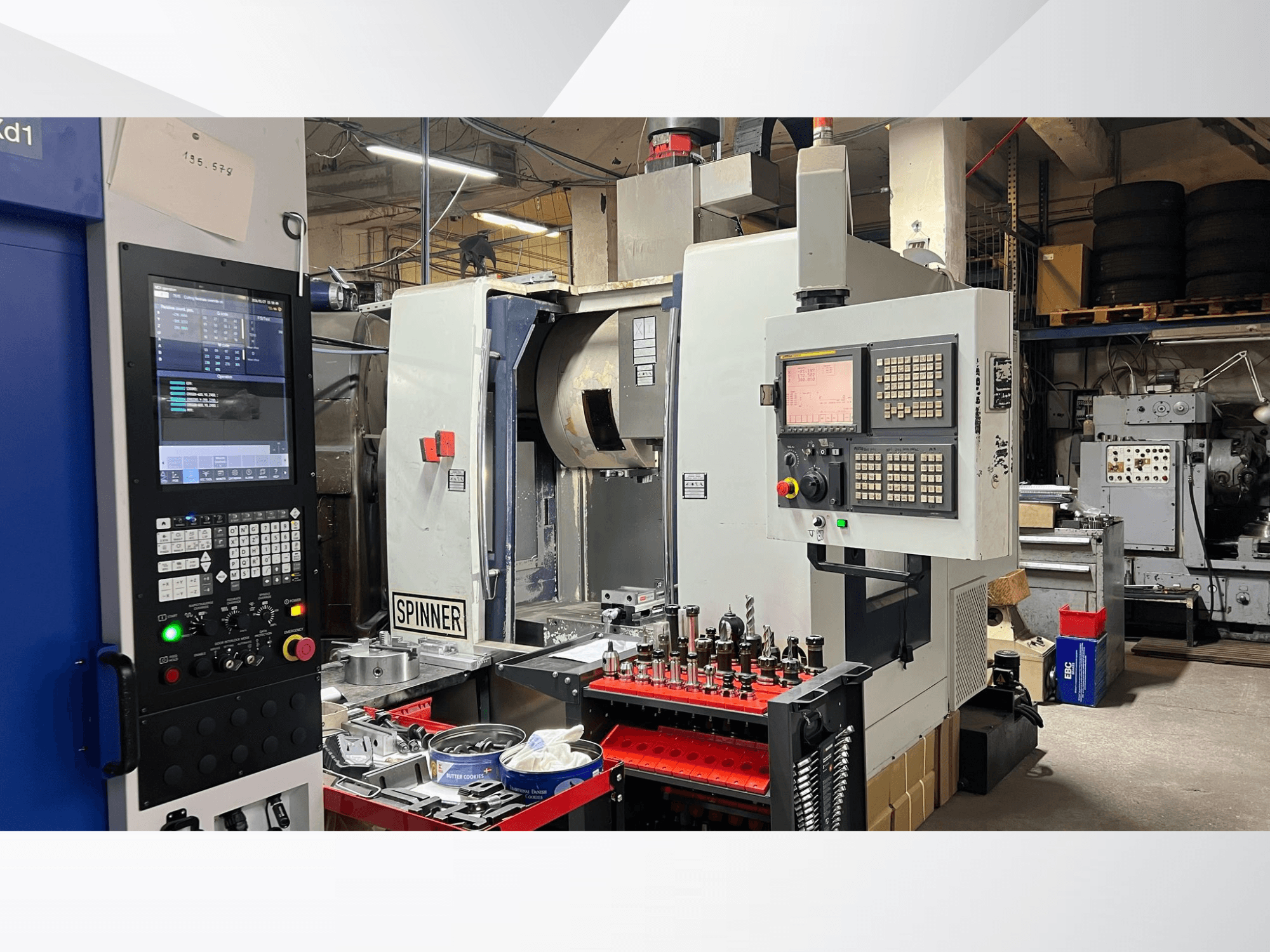 CNC-gép, amelyen a vezérlőpanel, a szerszámok és a munkadarabok láthatóak, szemből nézve, műhelykörnyezetben.