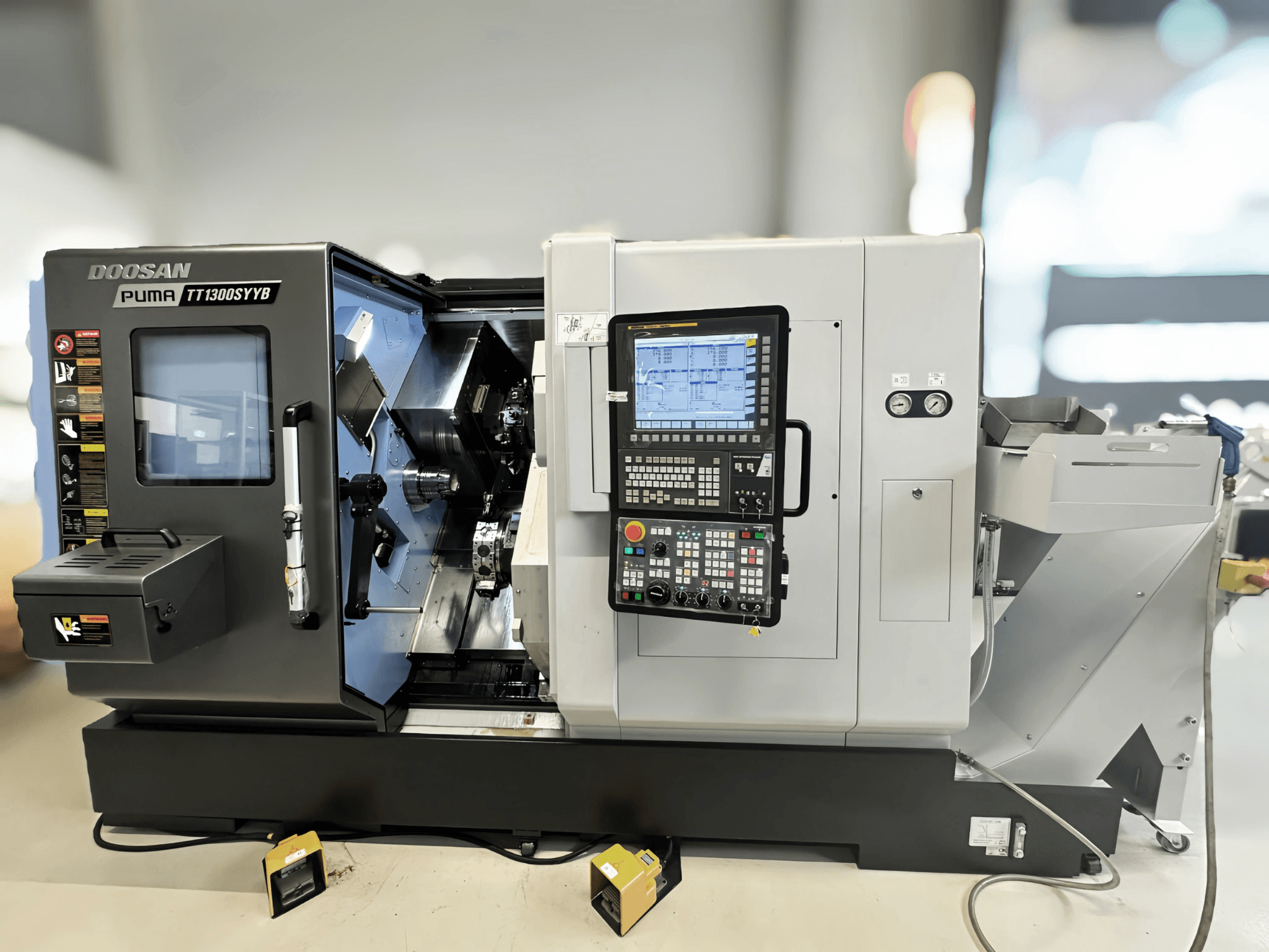 Doosan Puma TT1300SYYB esztergálóközpont oldalnézetben, a vezérlőpanel és a gép belseje látható a szerszámokkal.