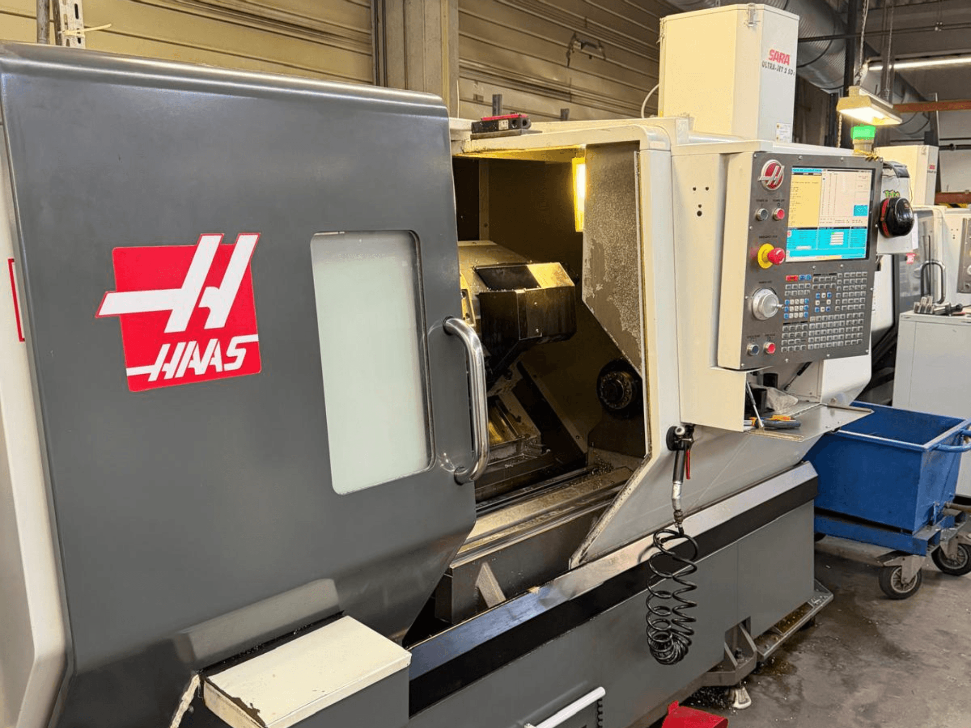 HAAS DS-30SSY vízszintes esztergagép, elölnézetben, a vezérlőpanel és a belső alkatrészek láthatóak, műhelyben.