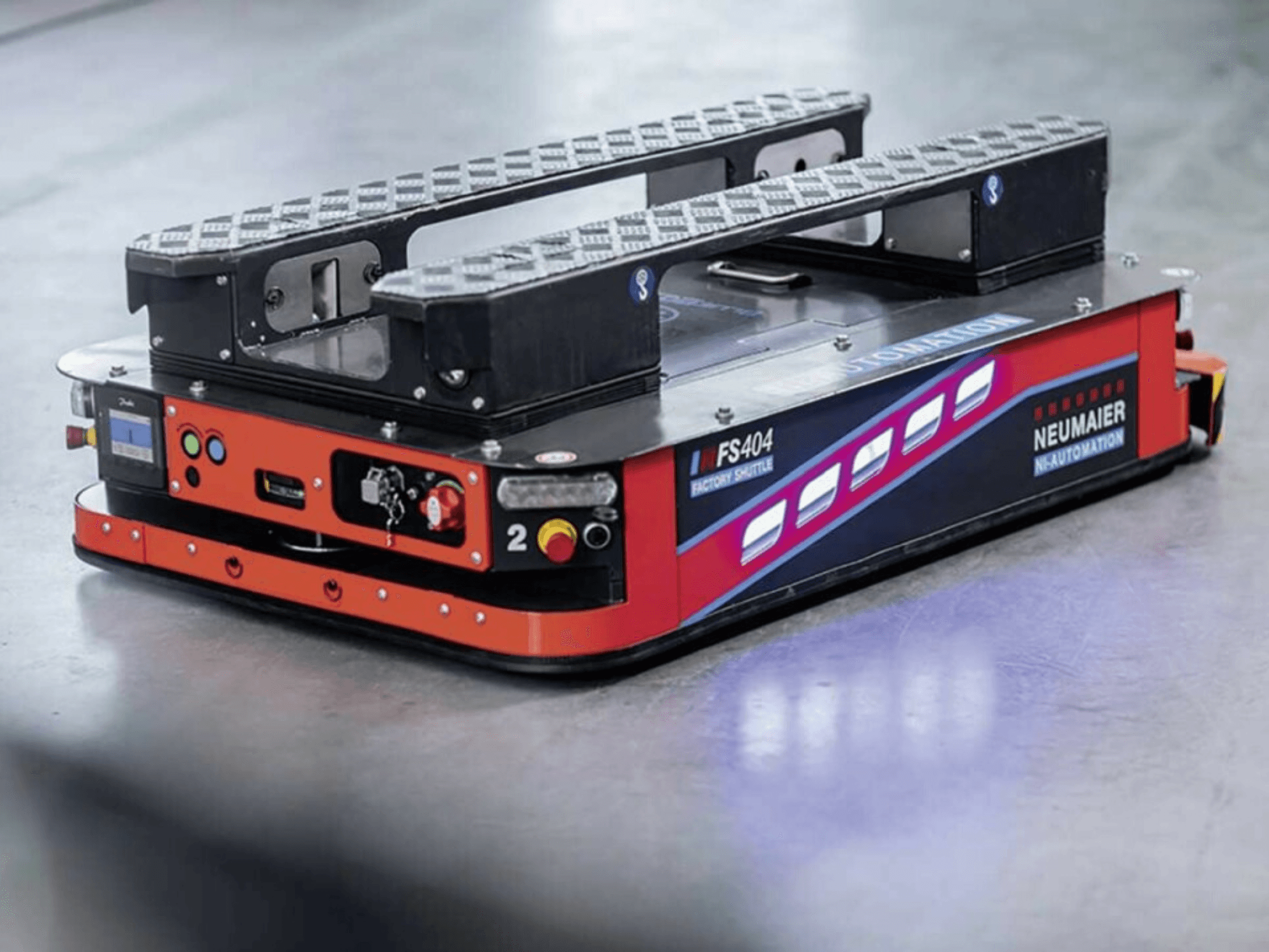 NEUMAIER AGV Factory Shuttle FS404, alacsony profilú raklapkezelő rendszer, oldalnézet a kerekekkel, kezelőszervekkel és biztonsági funkciókkal.