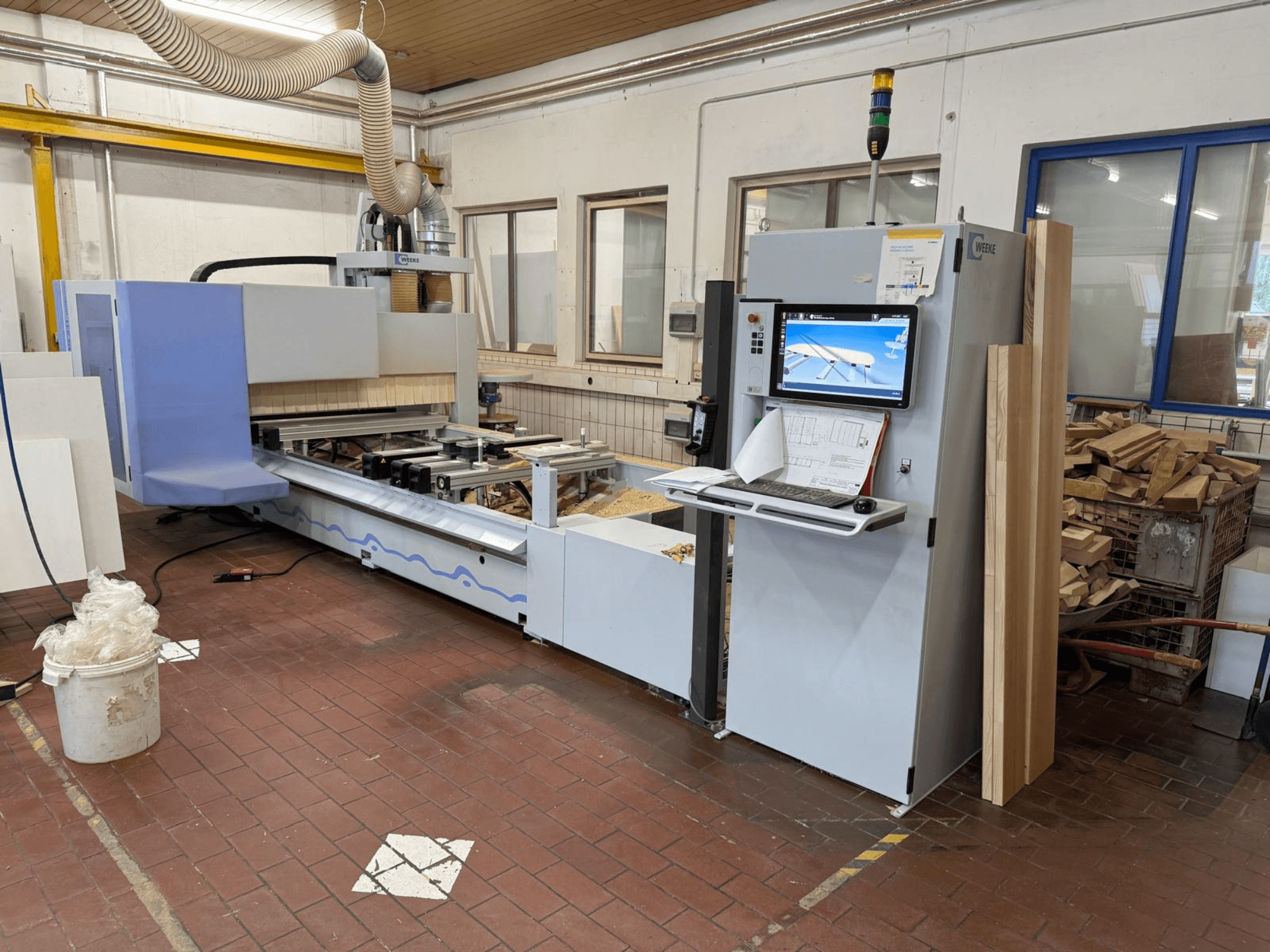 Weeke PROFI BMG211/32/12/K CNC faipari megmunkáló központ, elölnézet, vezérlőpanellel és fadarabokkal, porelszívó rendszerrel.