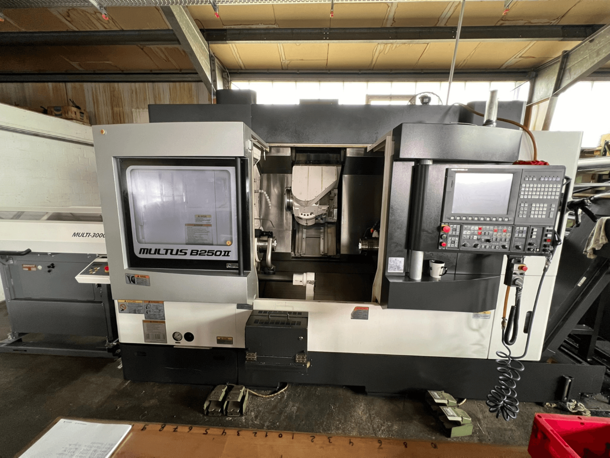 Okuma Multus B250II MW eszterga-marógép, elölnézet, a vezérlőpanel és a megmunkálási terület részleteinek bemutatásával.