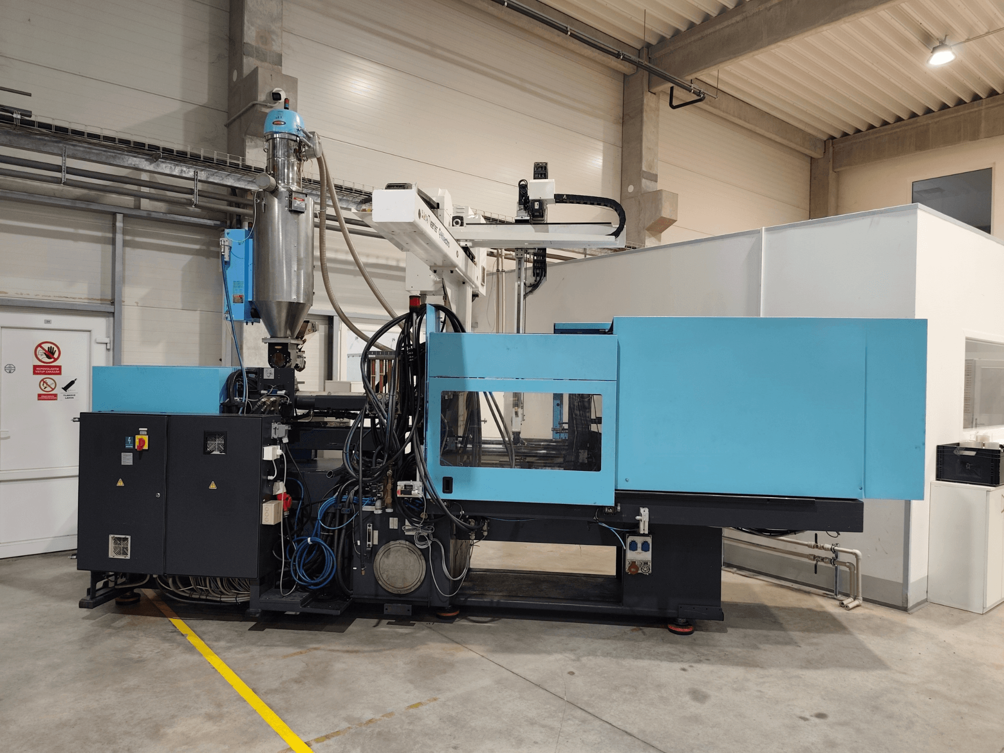 Egy DEMAG Ergotech Extra 160-430 hidraulikus fröccsöntőgép elölnézete, látható vezérlőpanellel és adagolótartállyal.
