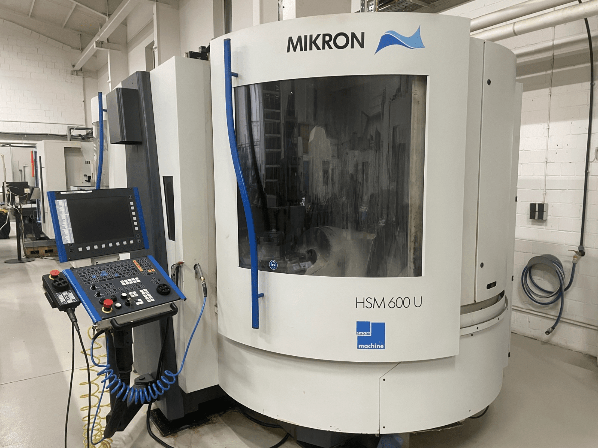 A MIKRON HSM600U függőleges megmunkálóközpont szemből, a kezelőpanel és a nagyméretű ablak látható.