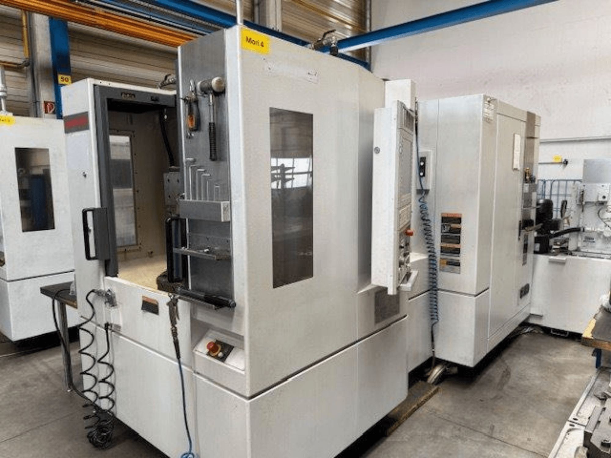 MORI SEIKI NH4000 DCG vízszintes megmunkálóközpont szemből, nyitott ajtóval és a vezérlőpanel részleteivel.