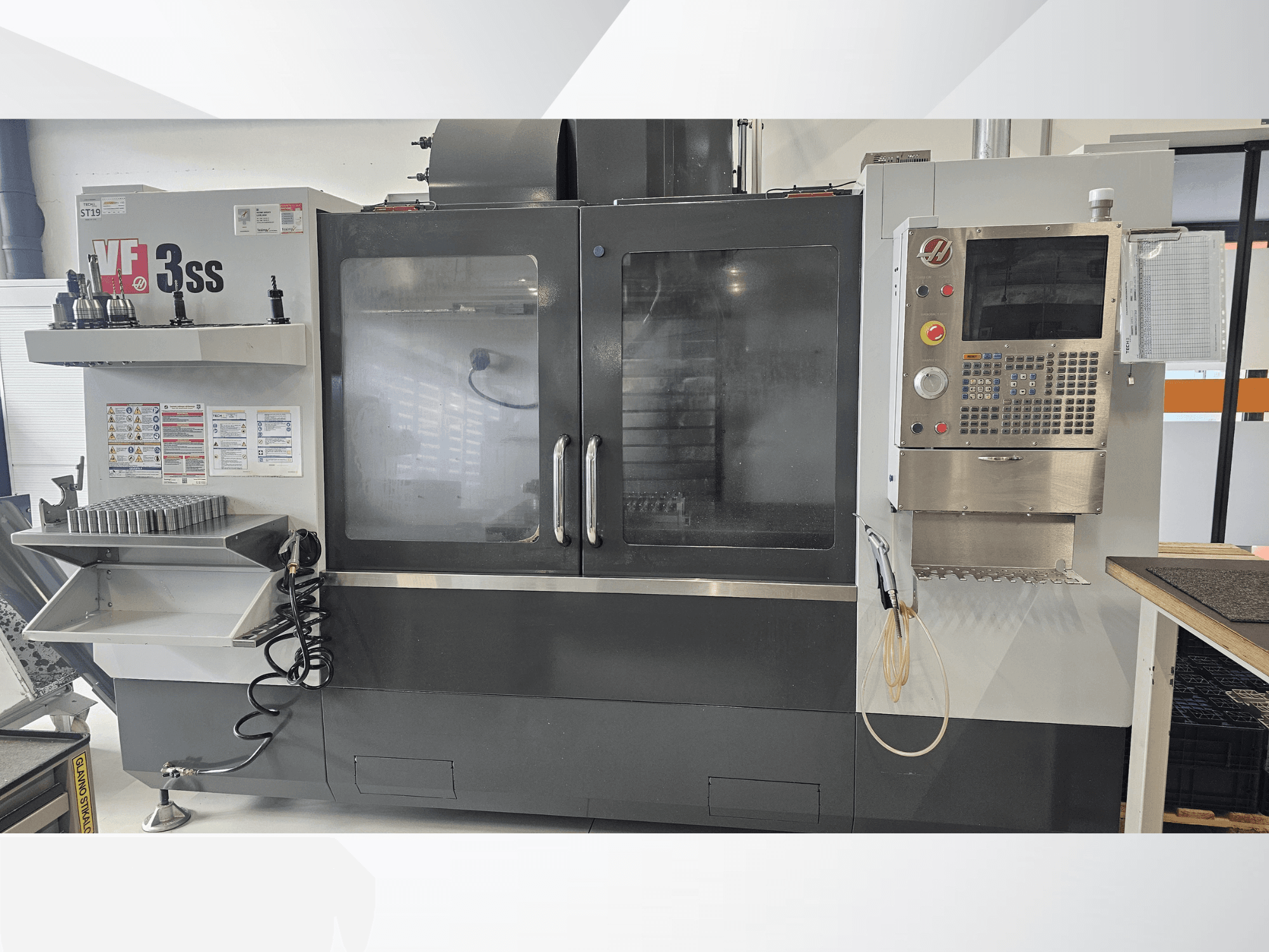 HAAS VF-3SS függőleges megmunkálóközpont, előlnézet, vezérlőpanel, szerszámtartó és nagy üvegajtó.