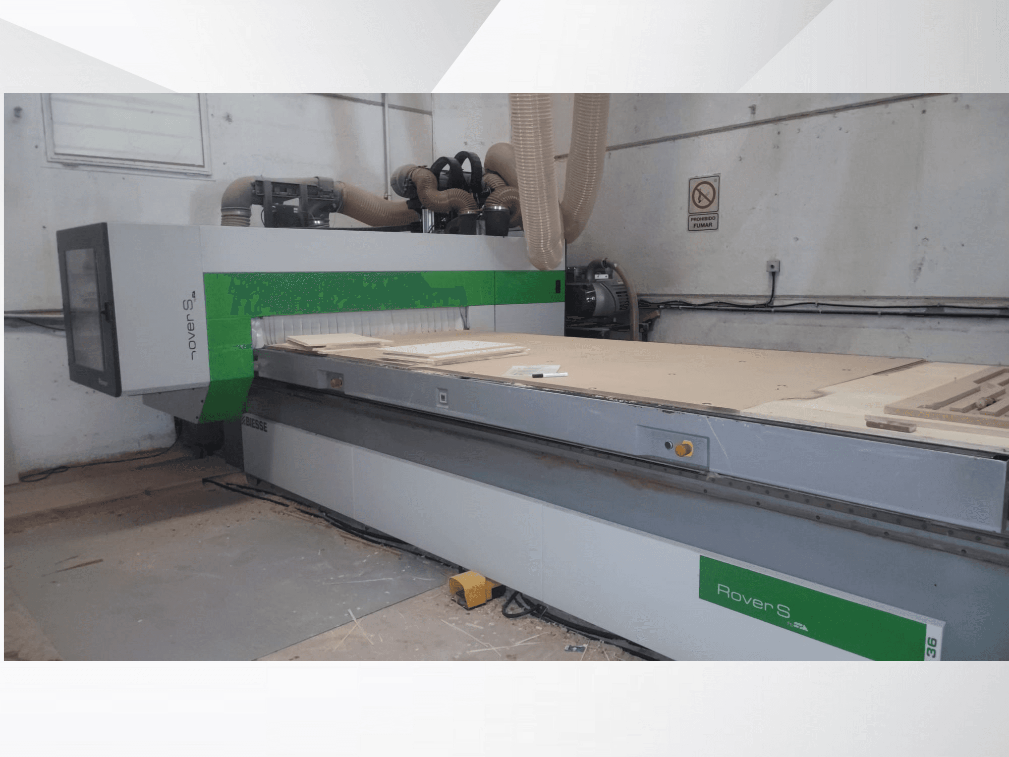 A Biesse Rover S CNC-gép elülső nézete, nagy munkafelülettel, fapanelekkel és porelszívó tömlőkkel.