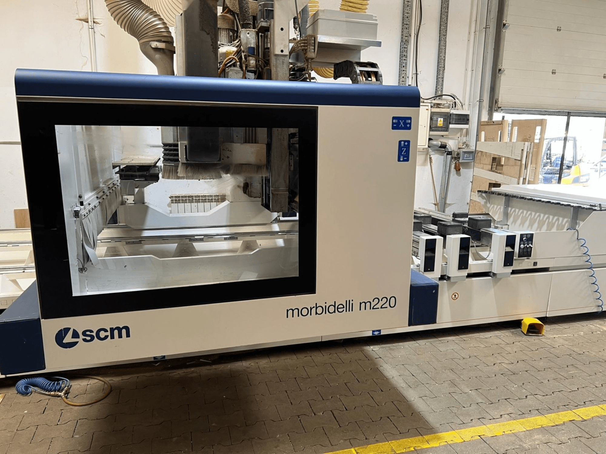 Az SCM Morbidelli M220 CNC megmunkálóközpont elölnézete, amelyen látható a nagy ablak, a vezérlőpanel és a munkaterület.