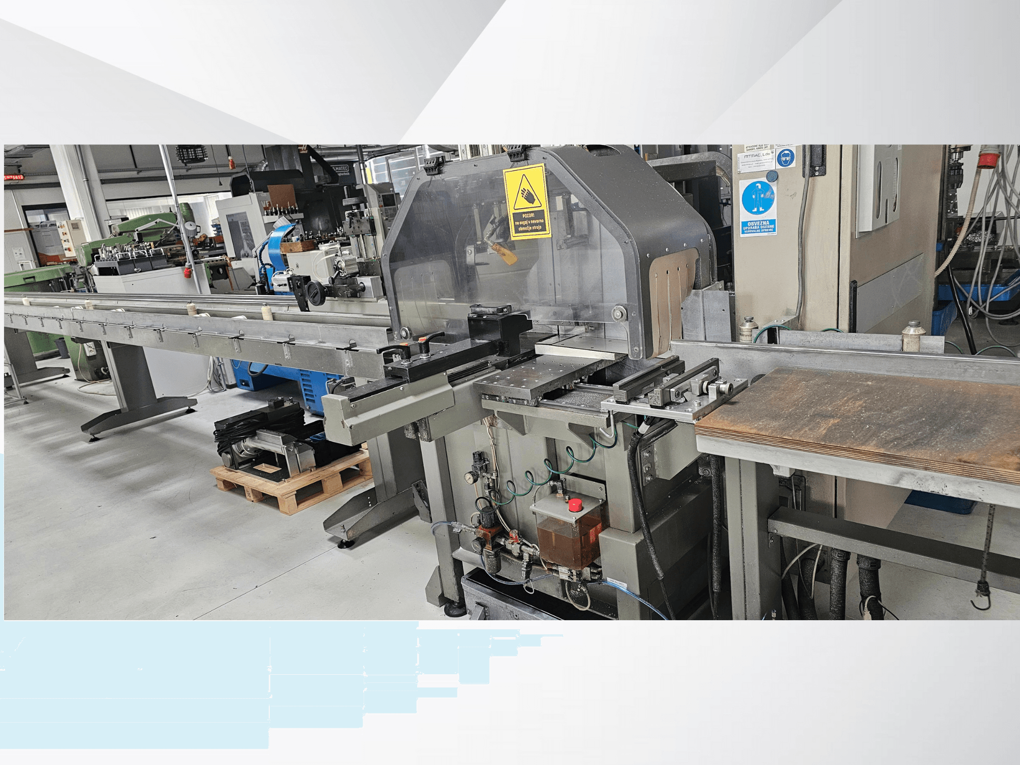 Ipari vágógép oldalnézetből, hosszú szállítószalaggal, vezérlőpanellel és biztonsági figyelmeztetésekkel.