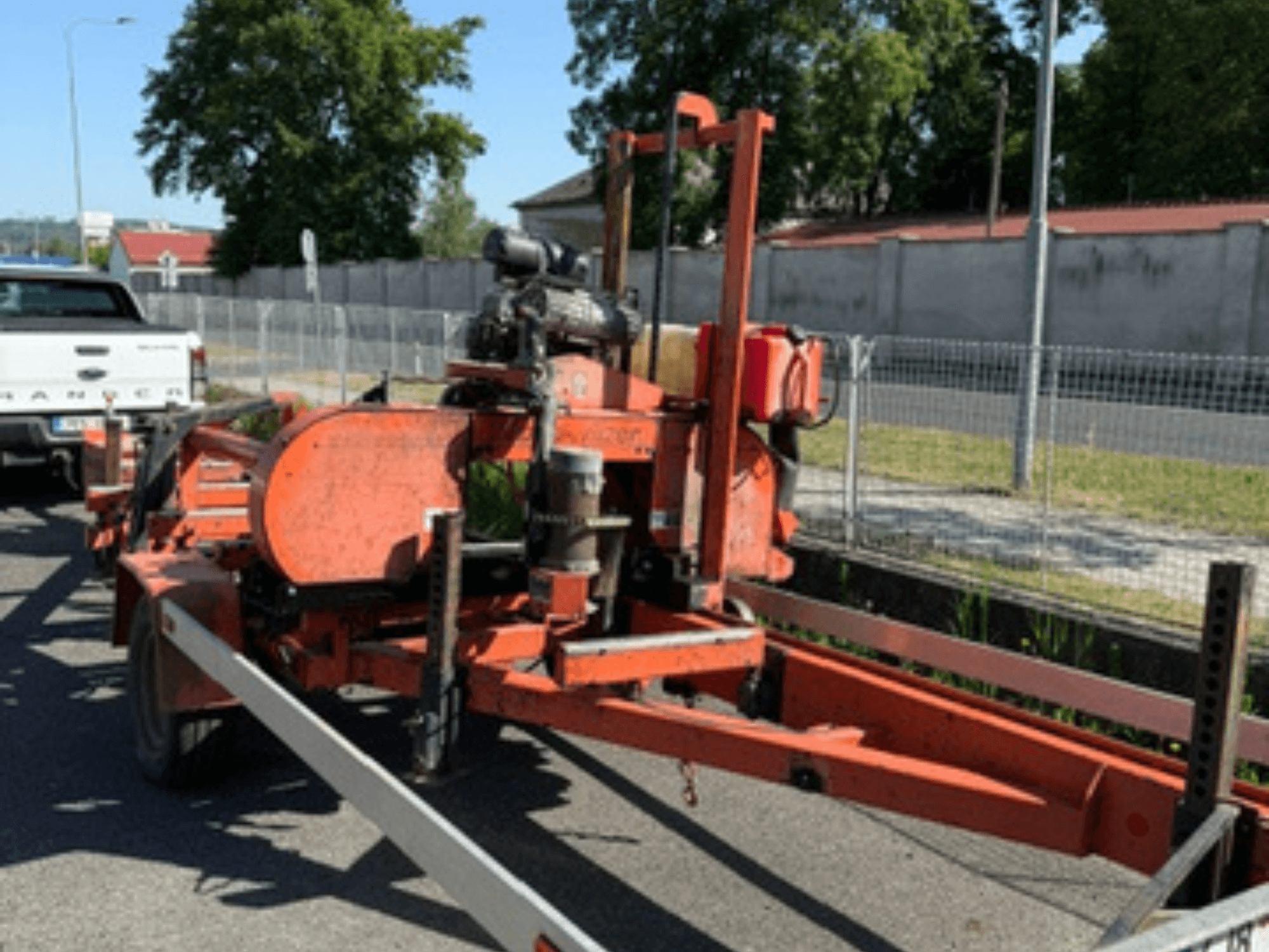 WOOD-MIZER LT40 fa szalagfűrész narancssárga színben, oldalnézetben egy pótkocsin, látható kerekekkel és motoralkatrészekkel.
