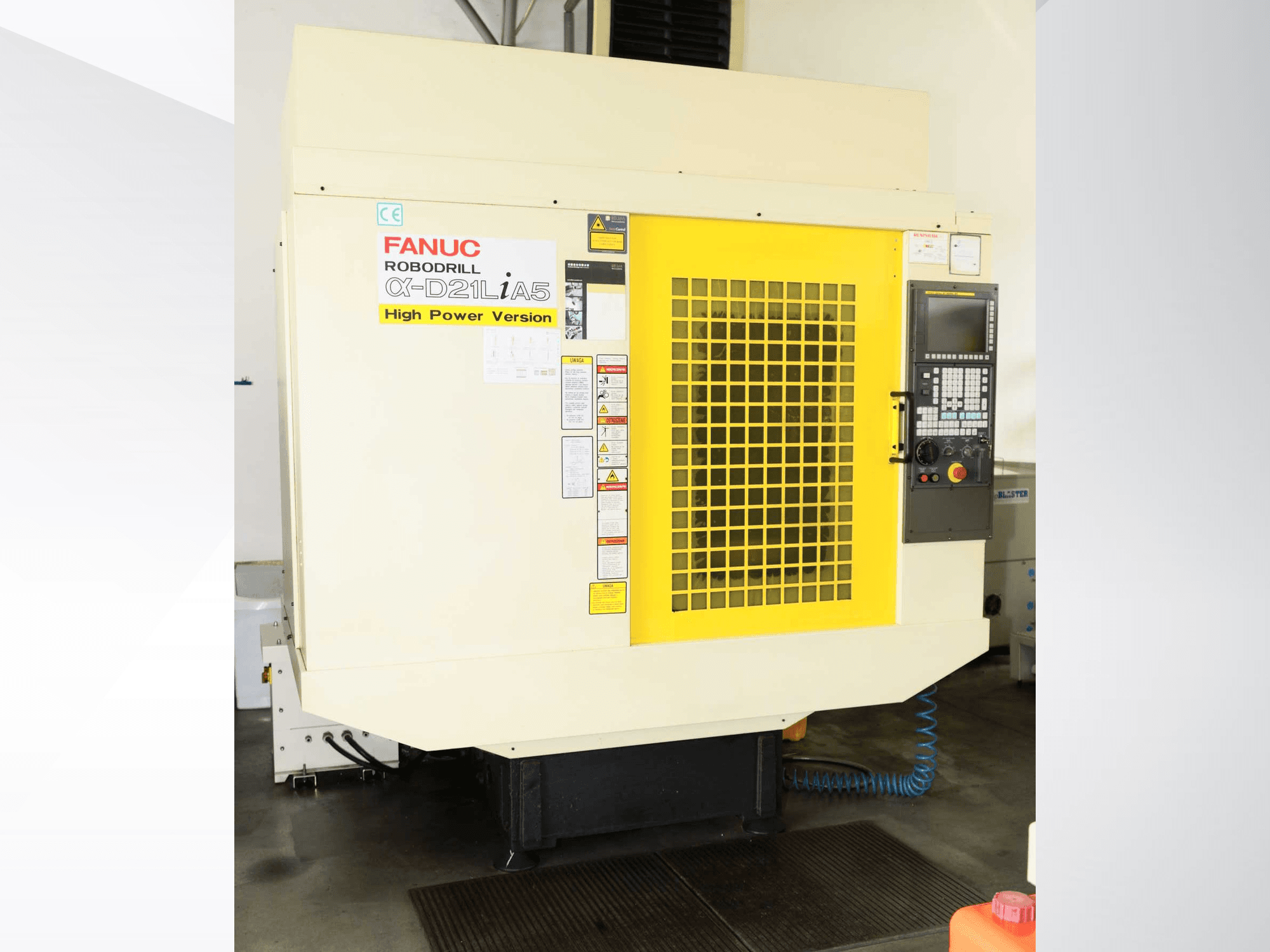 FANUC ROBODRILL α-D21LiA5 függőleges megmunkálóközpont, elölnézet sárga biztonsági rácsokkal és a vezérlőpanel részleteivel.