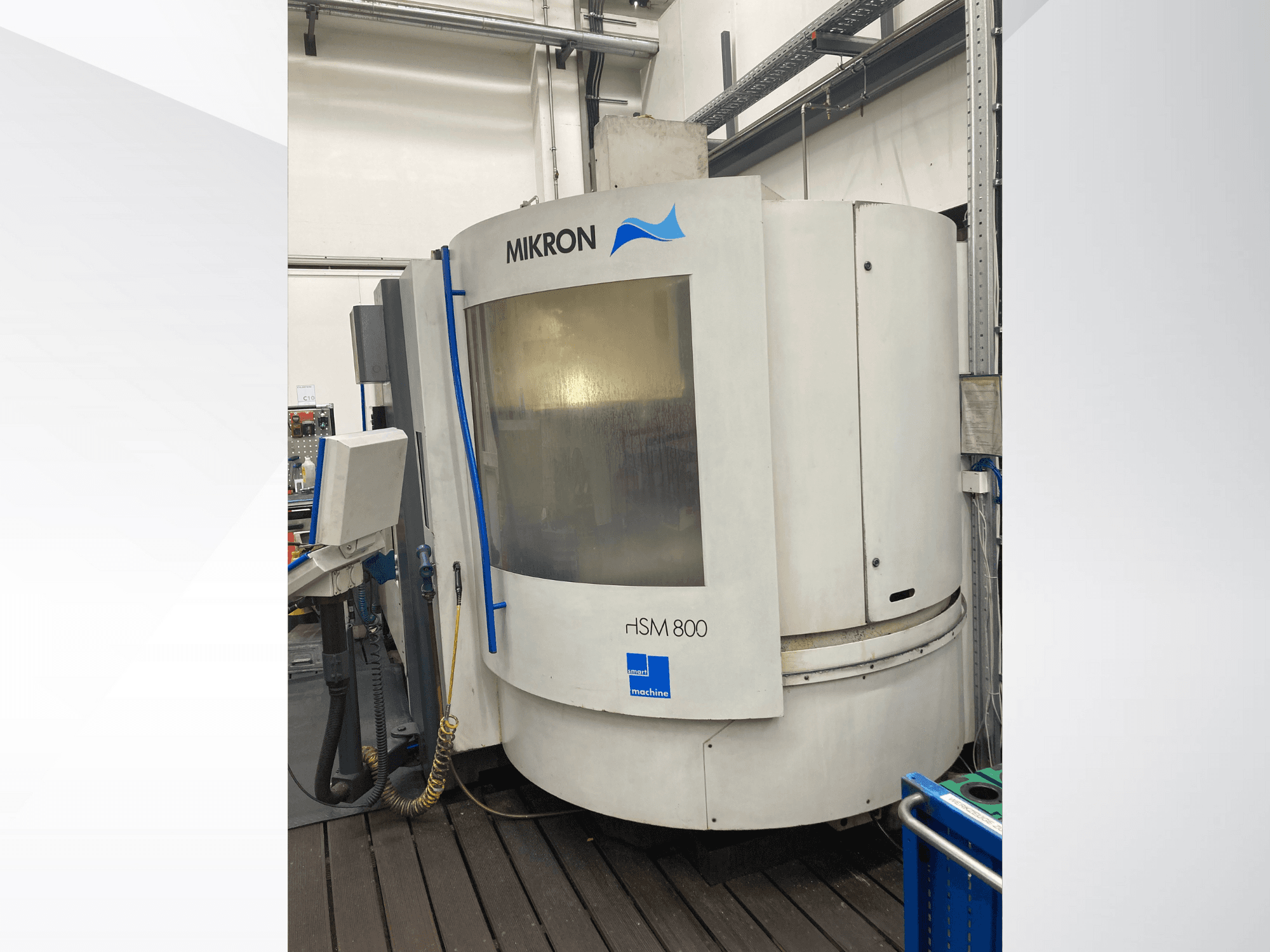 Mikron rISM 800 CNC-gép, elölnézet a vezérlőpanellel, hengeres kialakítással és kék ékezetekkel, műhelykörnyezetben.