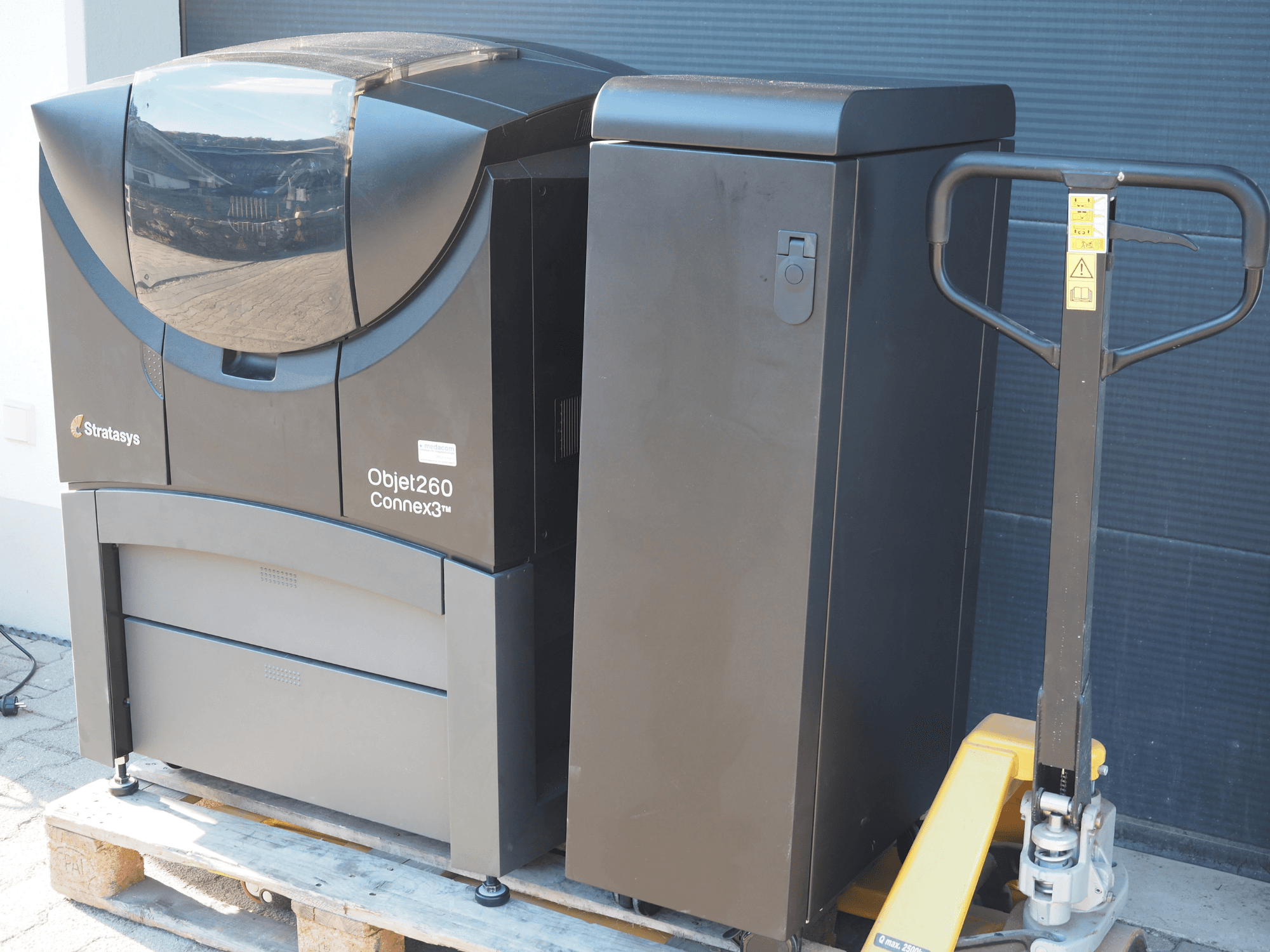 Stratasys Objet260 Connex3 műanyag 3D nyomtató, oldalnézet, kompakt kialakítás, vezérlőpanel és csatlakoztatott anyagtartály.