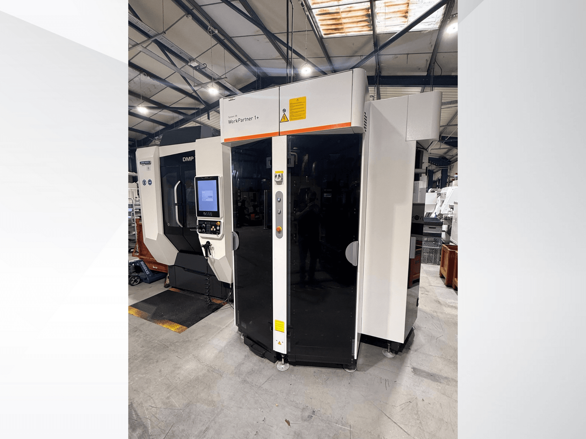 DMP WorkPartner 1+, előlnézet; érintőképernyős panellel és biztonsági jelzőkkel rendelkezik gyártási környezetben.