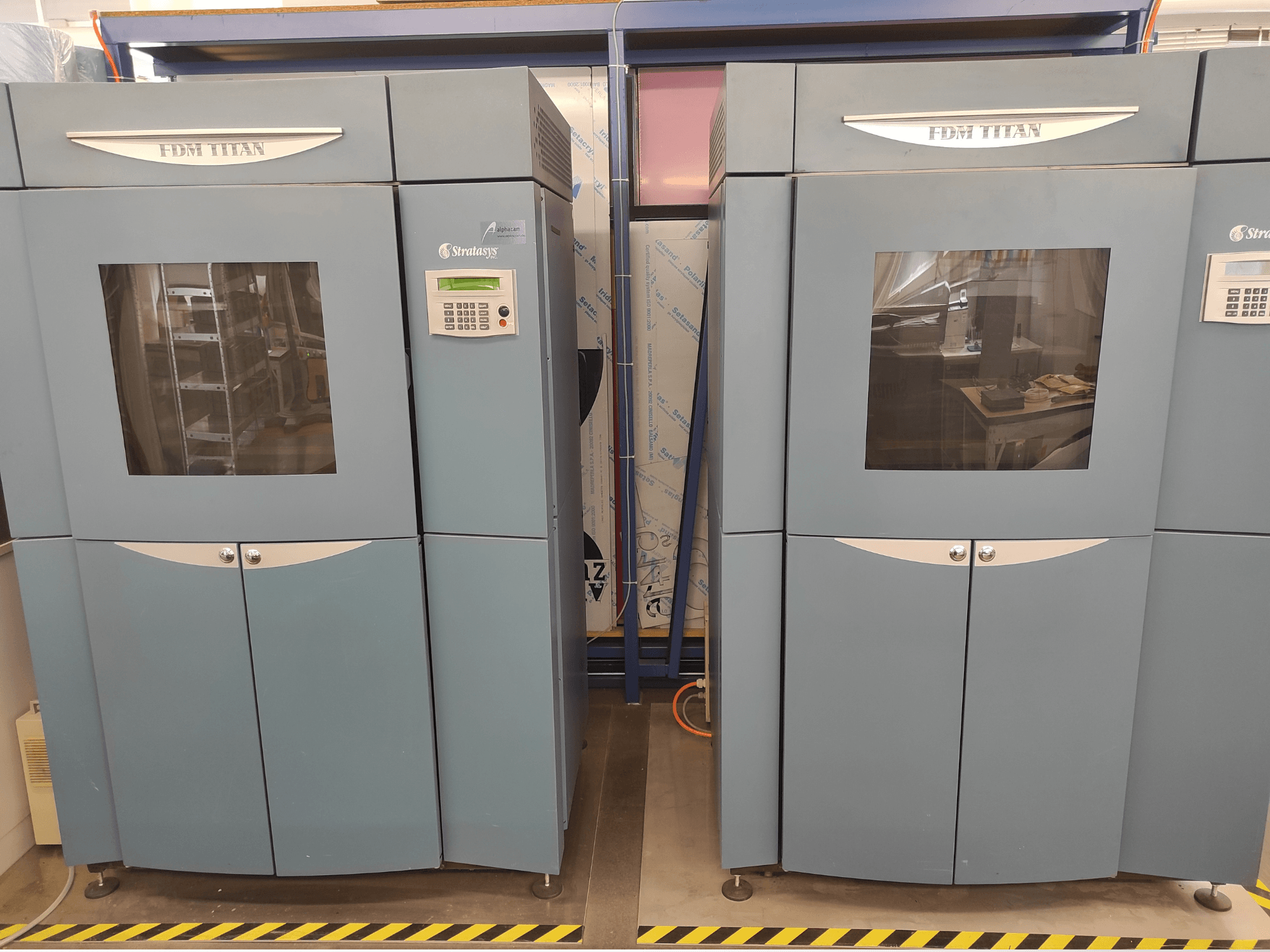 A Stratasys FDM TitanTI T0031 műanyag 3D-nyomtató elölnézete; kijelzőpanellel és átlátszó ablakkal rendelkezik.