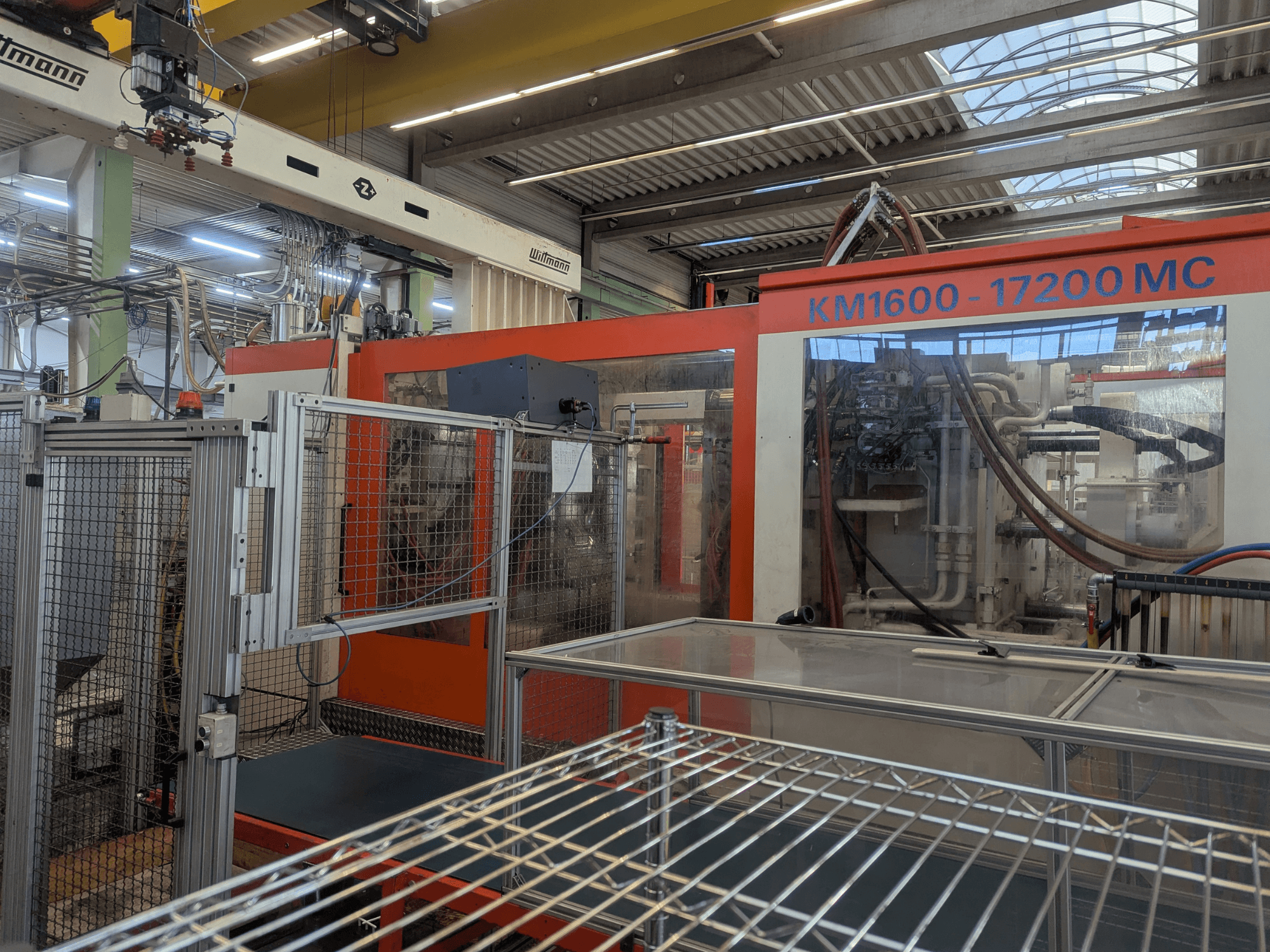 Krauss Maffei KM 1600-17200MC hidraulikus fröccsöntőgép, elölnézet a látható vezérlőpanellel és hidraulikavezetékekkel.