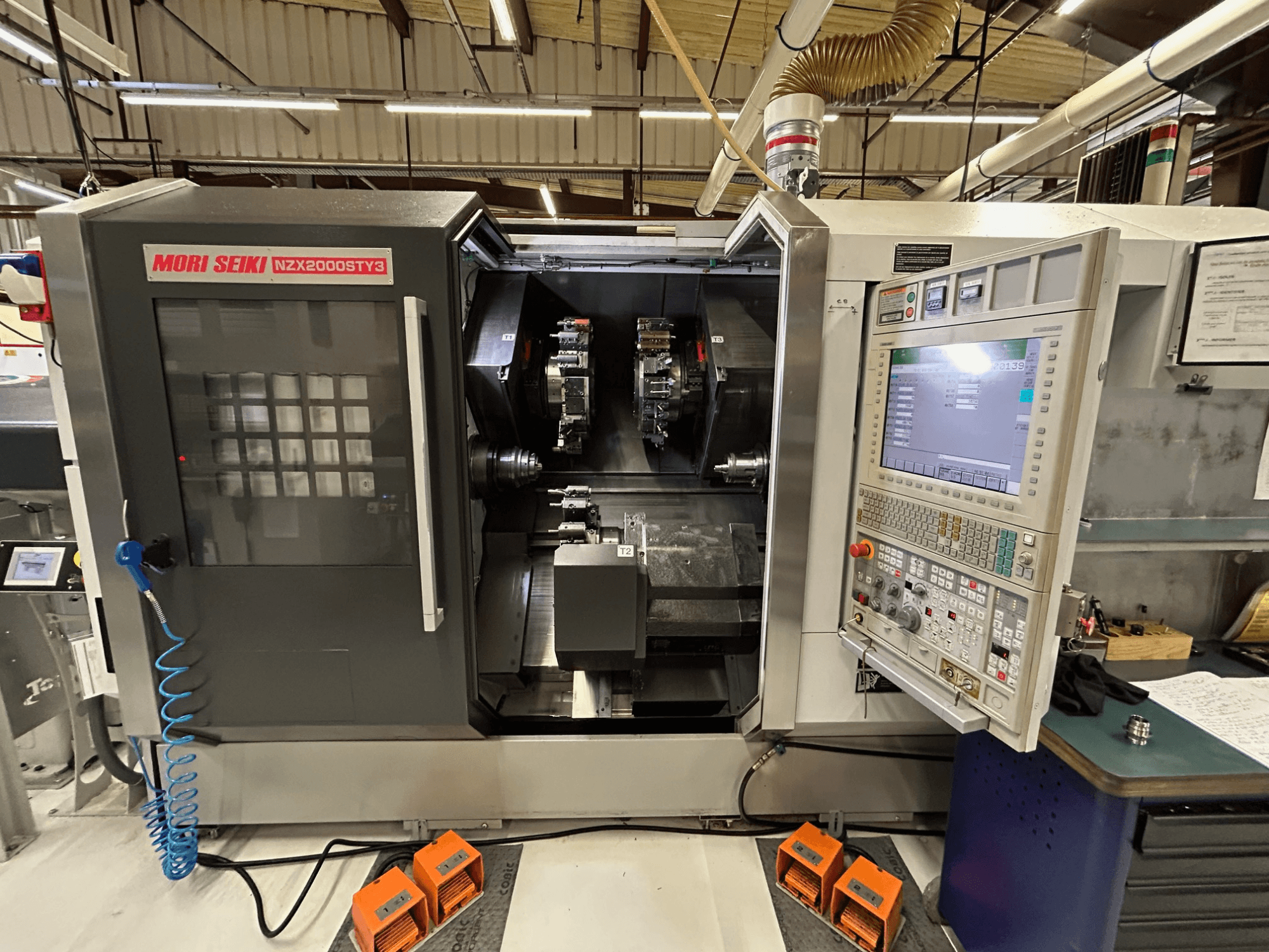 MORI SEIKI NZ2000 ST3Y3 többorsós eszterga, elölnézet, amelyen látható a vezérlőpanel és a megmunkálási terület.