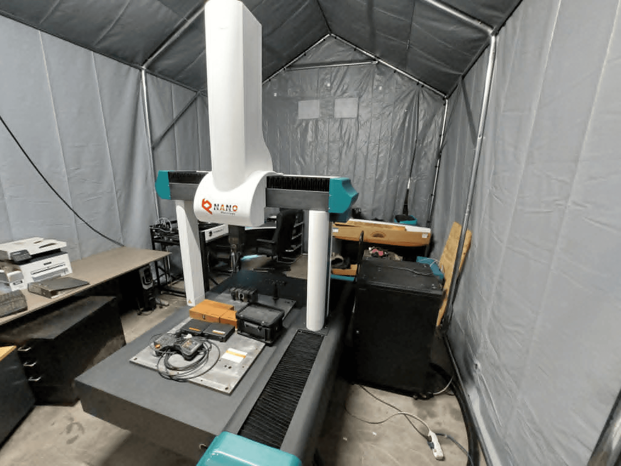 NANO METROLOGY Micr 7106 CMM sátorban; elölnézetben a gép karja és a mérőplatform a tartozékokkal.