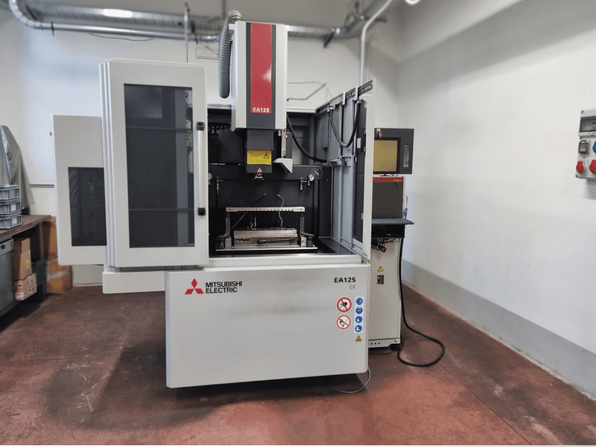 Mitsubishi Electric EA12S huzalvágó gép, elölnézet, nyitott ajtók, vezérlőpanel és biztonsági címkék.