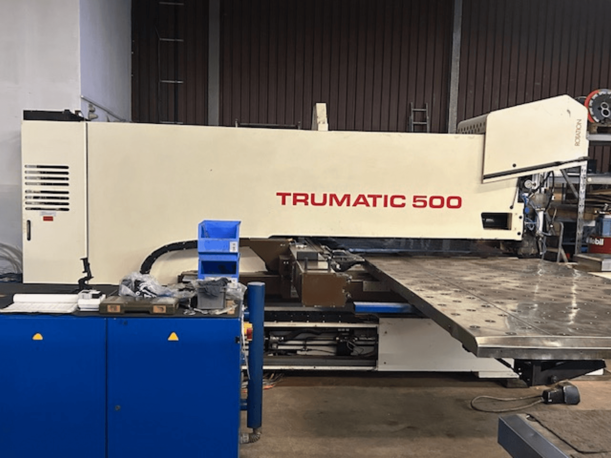 TRUMPF TRUMATIC 500 CNC lyukasztógép, elölnézetből, vezérlőpanellel és nagy, perforált felületet megjelenítő munkaasztallal.