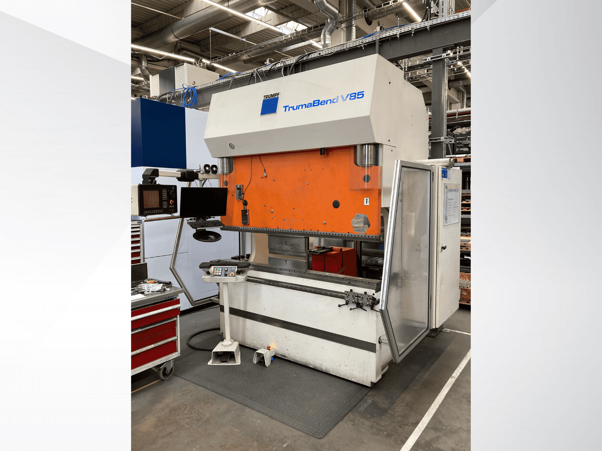 TruMatic V85 hajlítógép egy gyárban, narancssárga előlappal, vezérlőképernyővel és nyitott oldalajtóval, oldalnézetből.