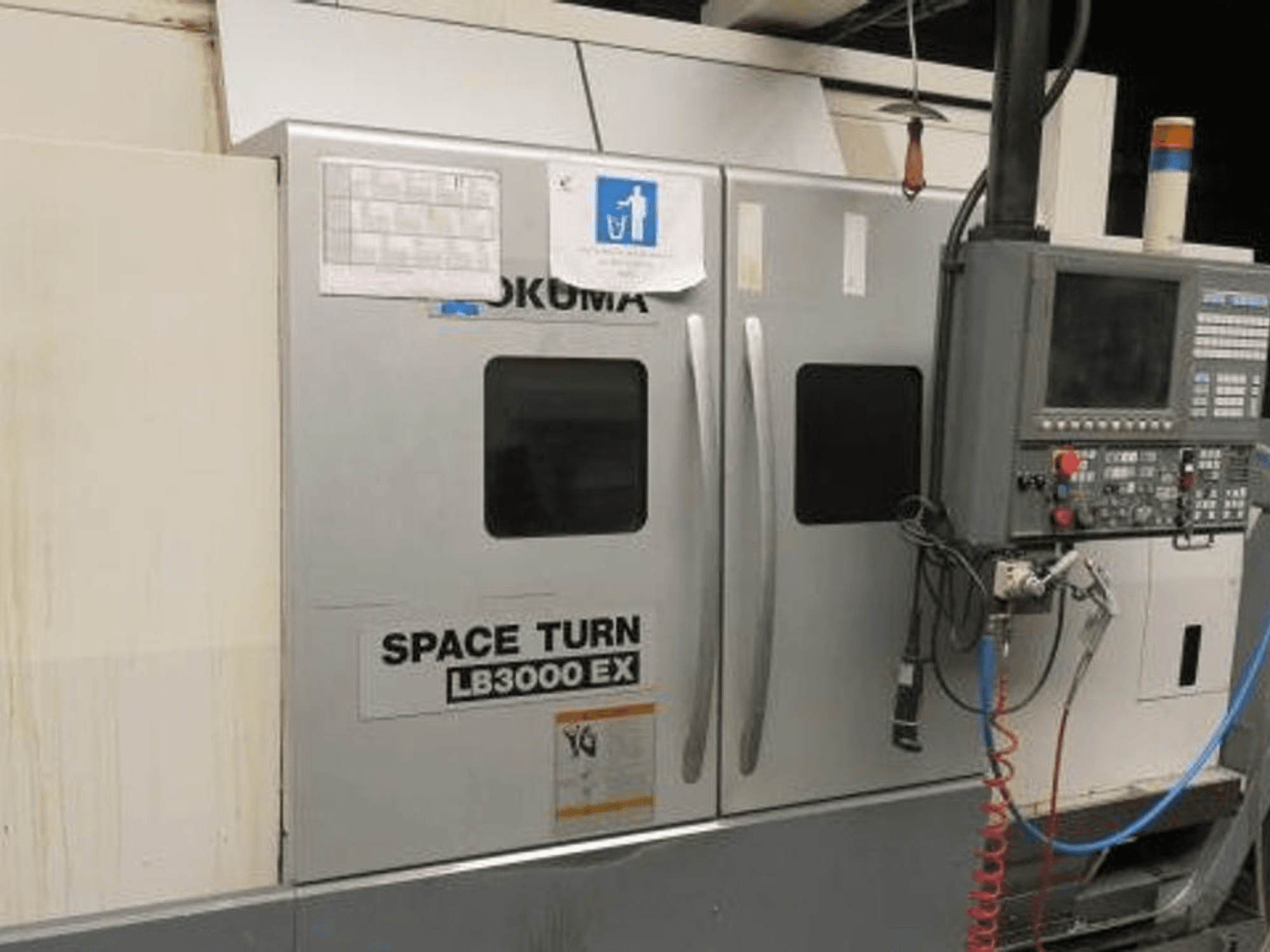Okuma Space Turn LB3000 EX CNC eszterga, oldalnézet, vezérlőpanel, két ajtó és látható kábelezés.