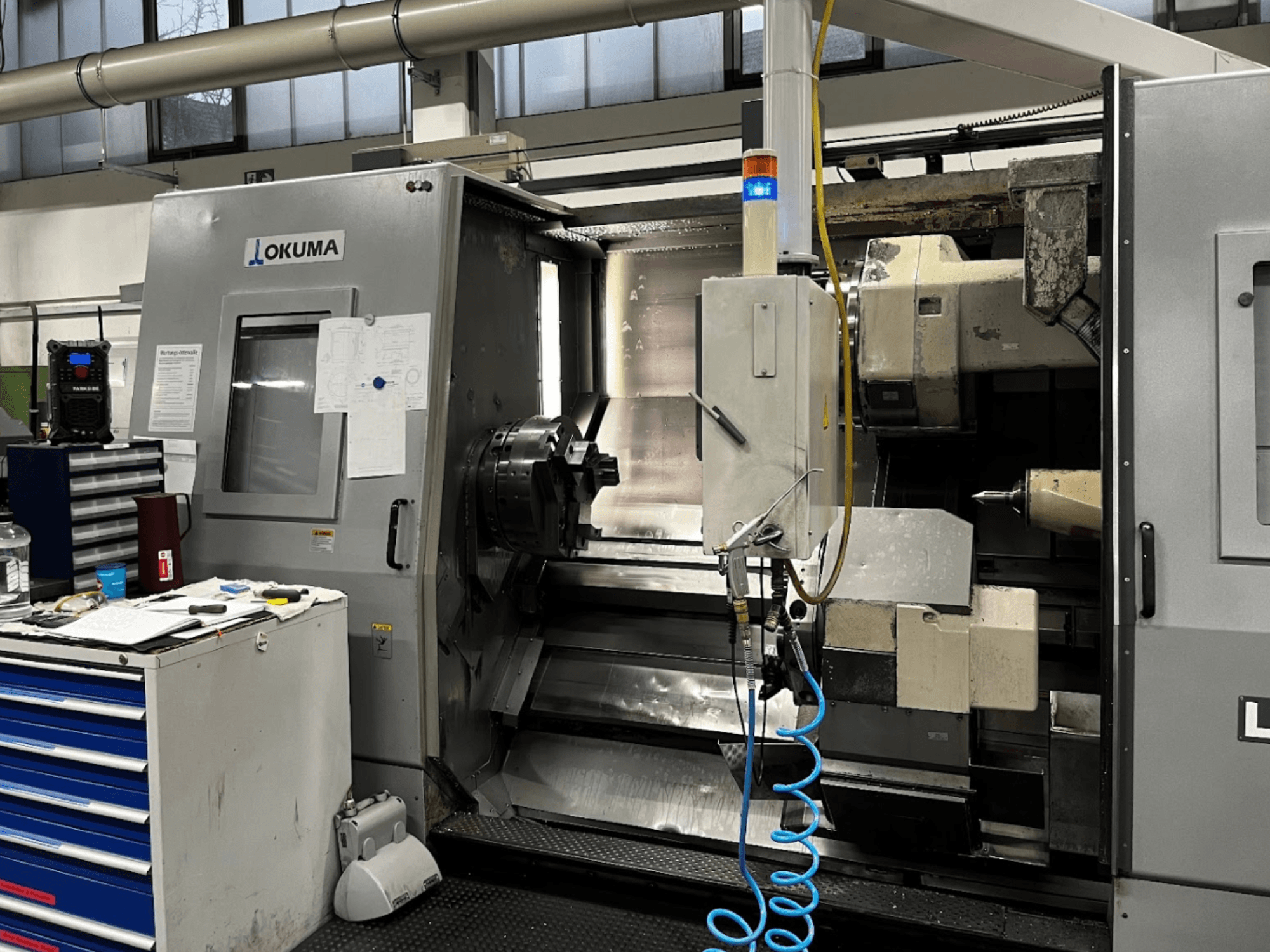 Okuma LU35-M vízszintes esztergagép, elölnézet. Vezérlőpanel, szerszámok és nagyméretű tokmány a megmunkálási műveletekhez.