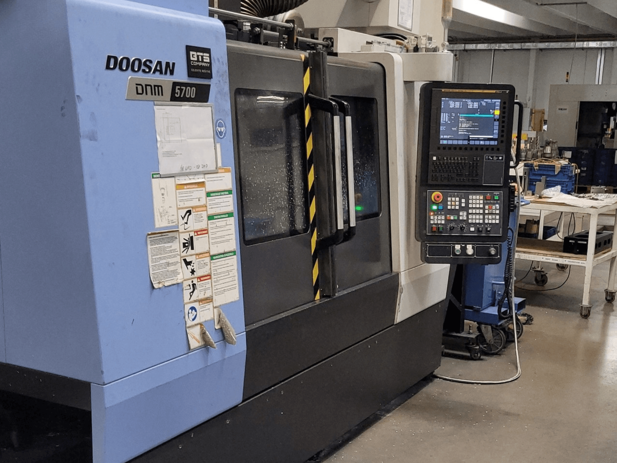 DOOSAN DNM 5700 függőleges megmunkáló központ, elölnézet, a vezérlőpanellel és a kezelőszervekkel.